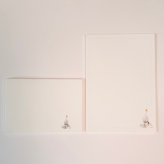 A white stationery set with a small illustrated duck at the bottom right corner, displayed against a plain white background.